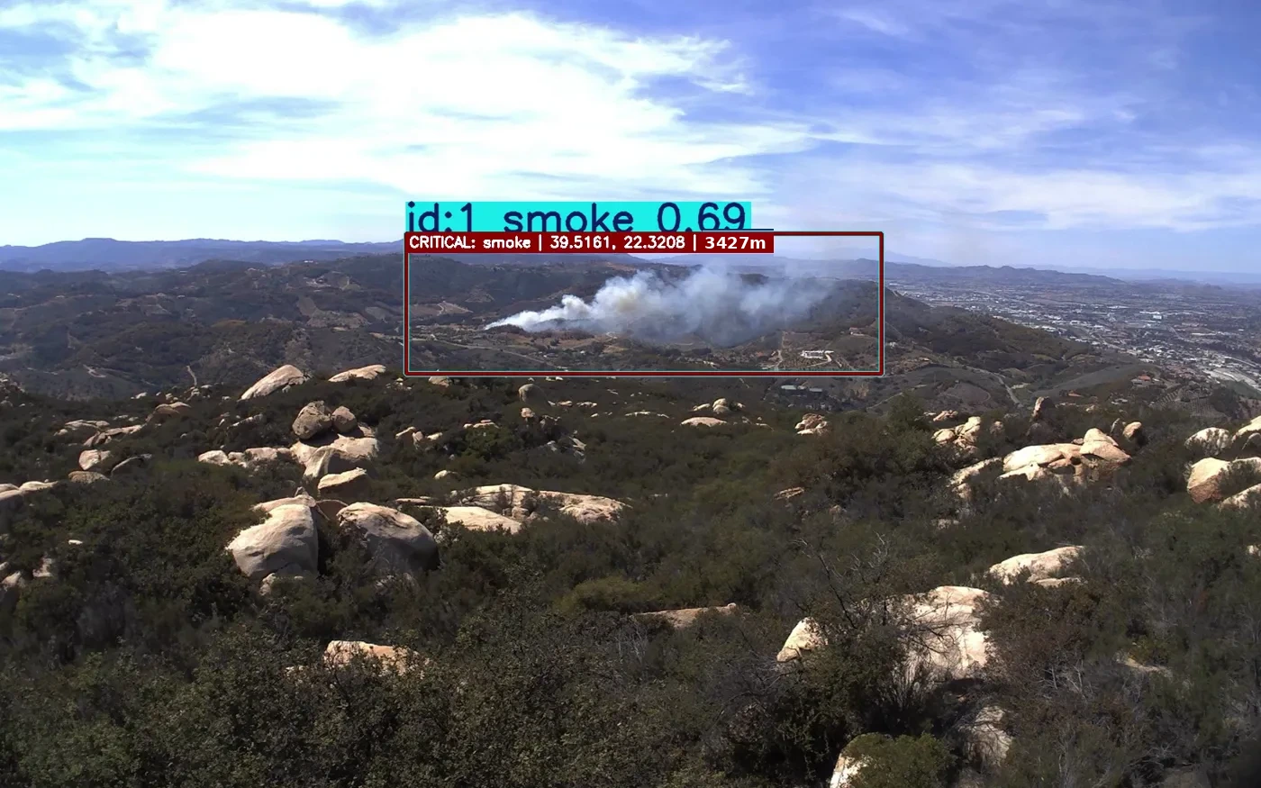 Distant smoke plume in a valley, detected by the AI and graded CRITICAL with GPS coordinates and range